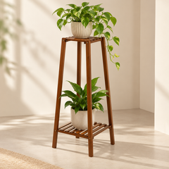 Bamboo plant stand with trailing pothos on the top shelf and a leafy plant below in a bright minimal room