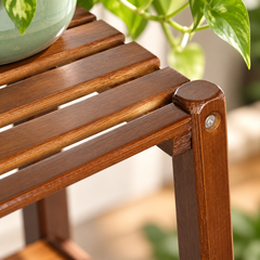 Close-up of the slatted bamboo shelf, rounded leg top and screw on a brown plant stand