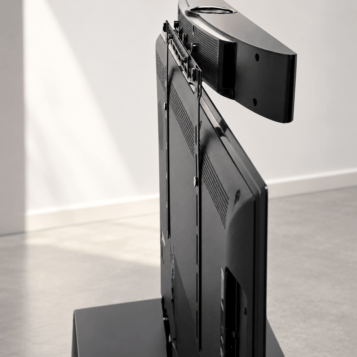 Back of a TV on a stand with black brackets holding a soundbar above the TV